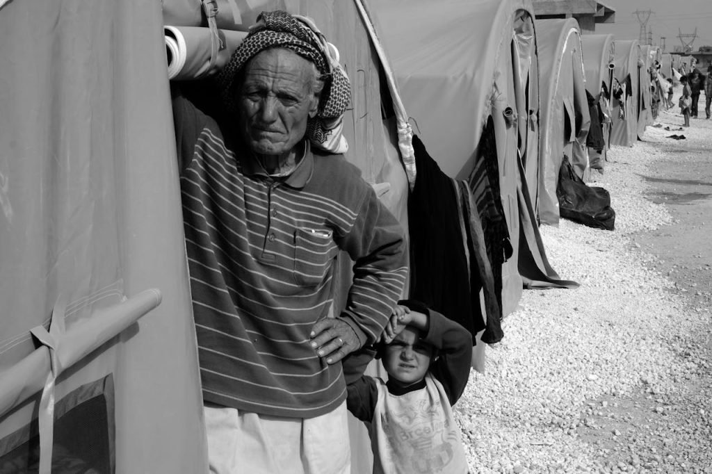 Black and white image of refugees in a camp, highlighting humanity and resilience.